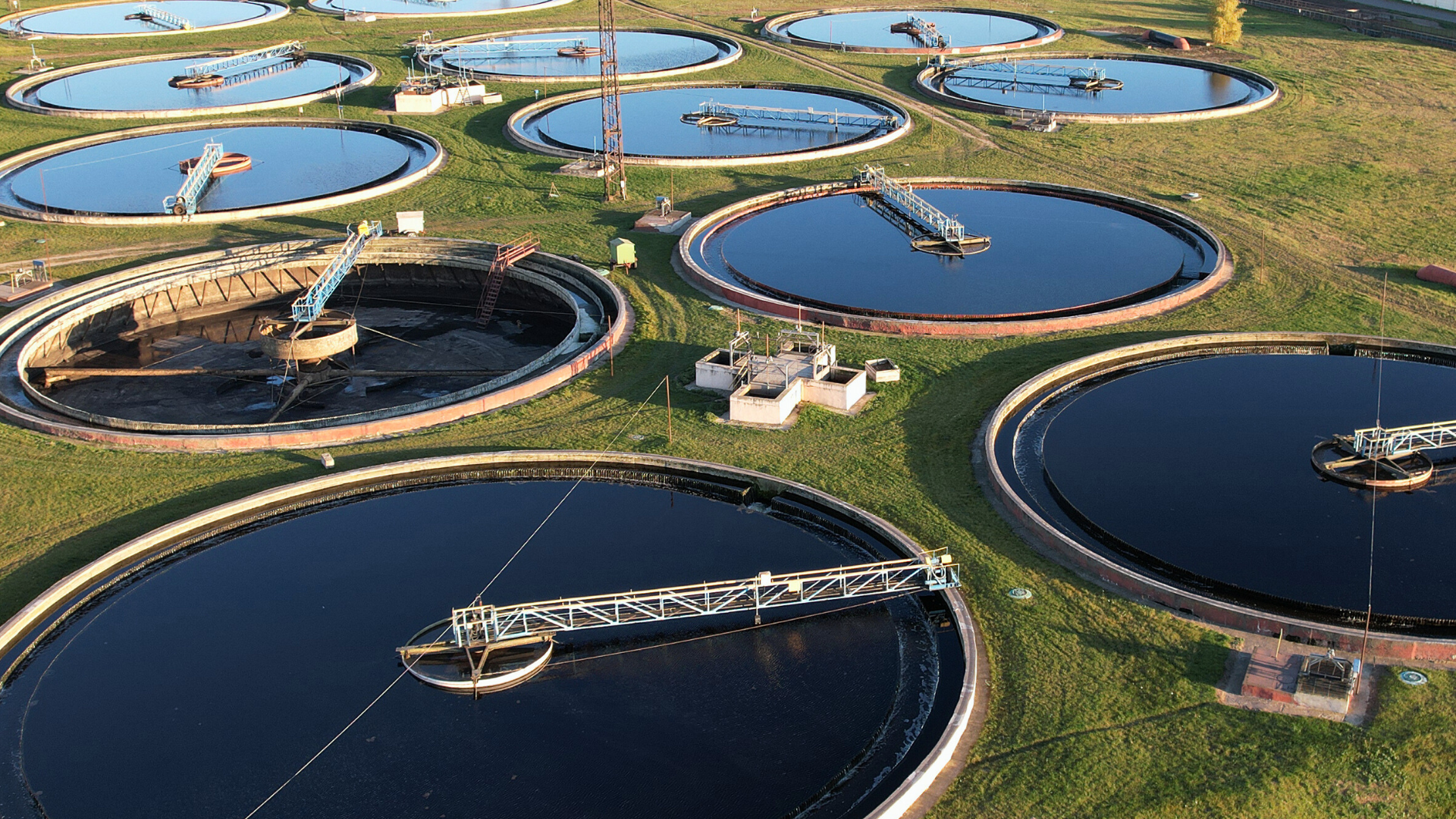 Vista aérea de tanques circulares en una planta de tratamiento de aguas y residuos, mostrando procesos de depuración y sedimentación.
